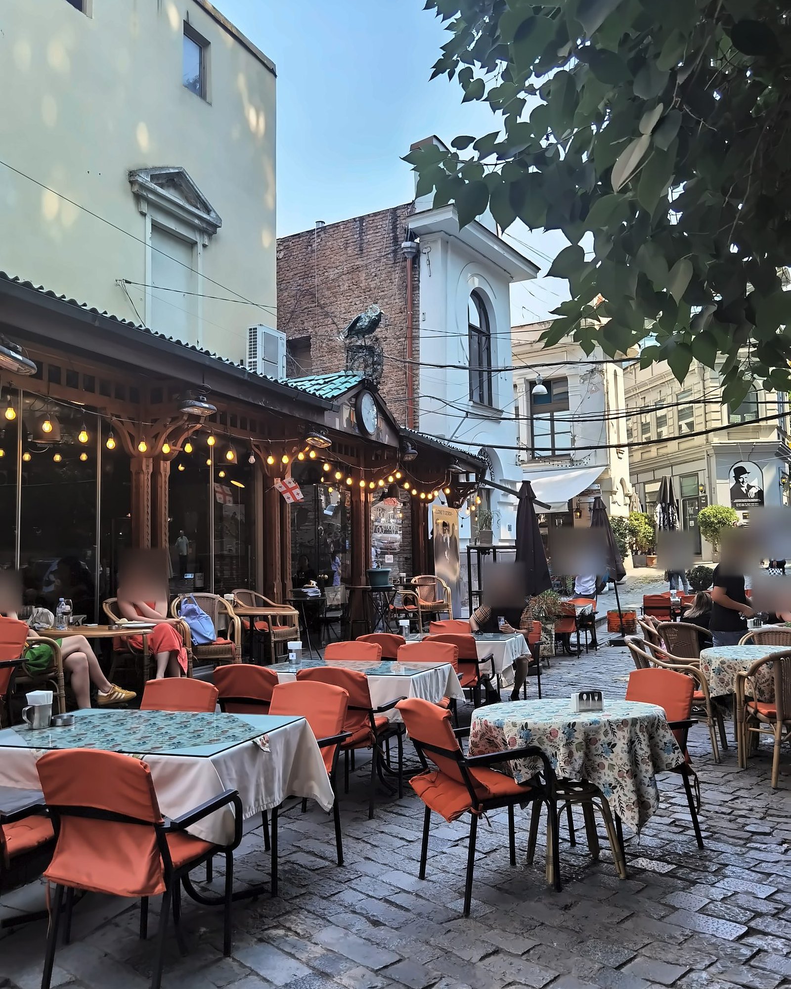 Straßencafé mit orangefarbenen Stühlen in der Altstadt von Tiflis