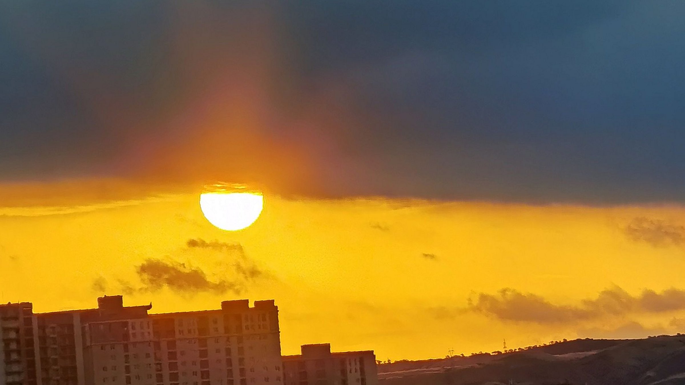 Sonnenuntergang über Tiflis mit Hochhäusern und Bergen im Hintergrund